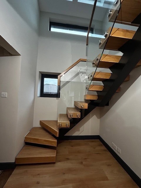 Modern wooden staircase with glass balustrade in a contemporary home.