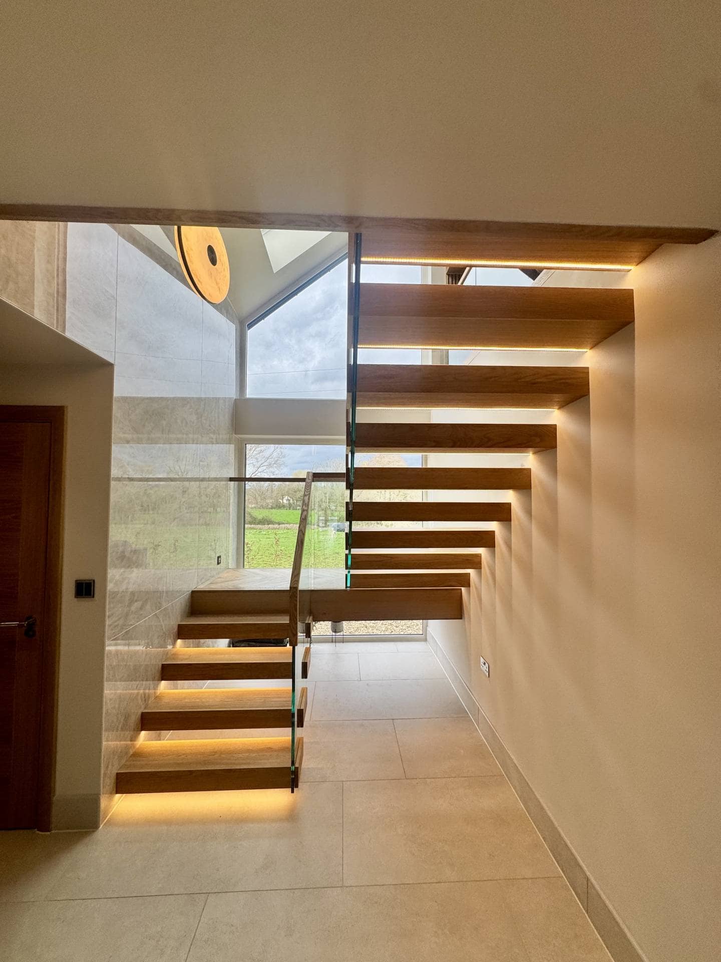 Modern wooden staircase with glass balustrade in a contemporary home.