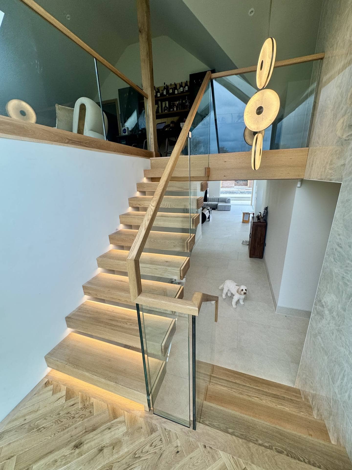Stylish wooden staircase with glass railing, leading to an upper floor in a modern interior.