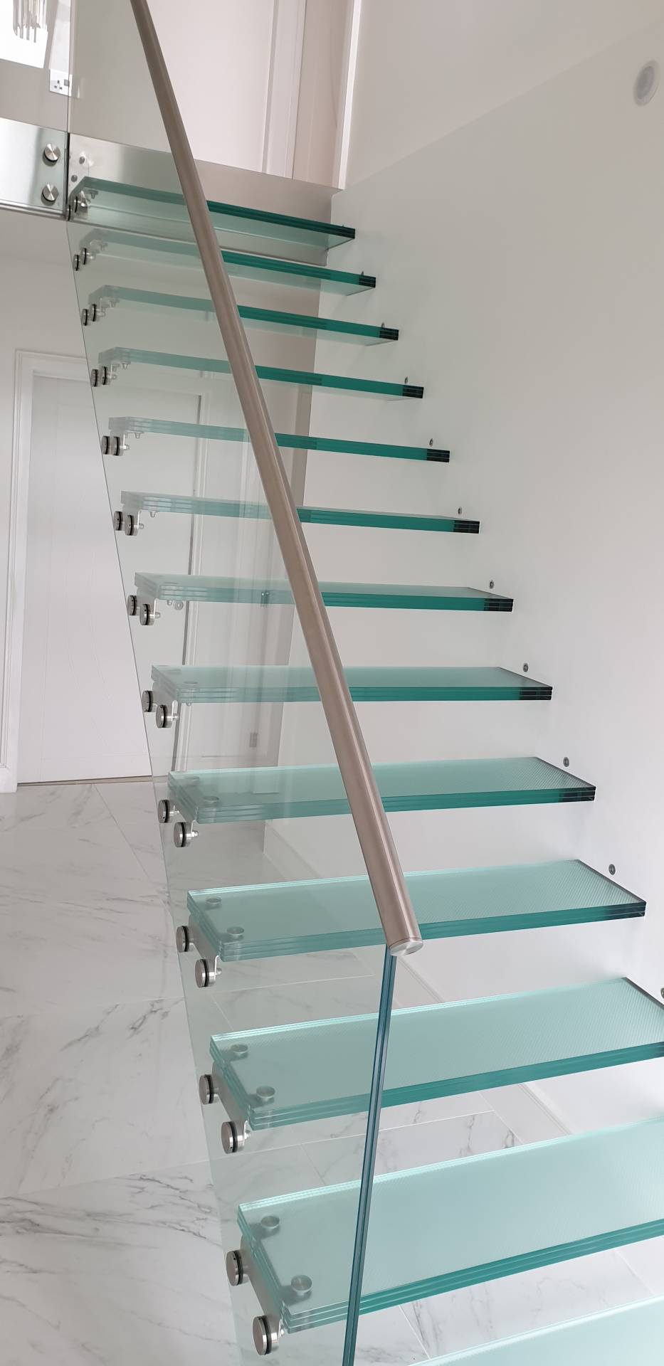 Elegant glass staircase with stainless steel handrail in a modern interior.